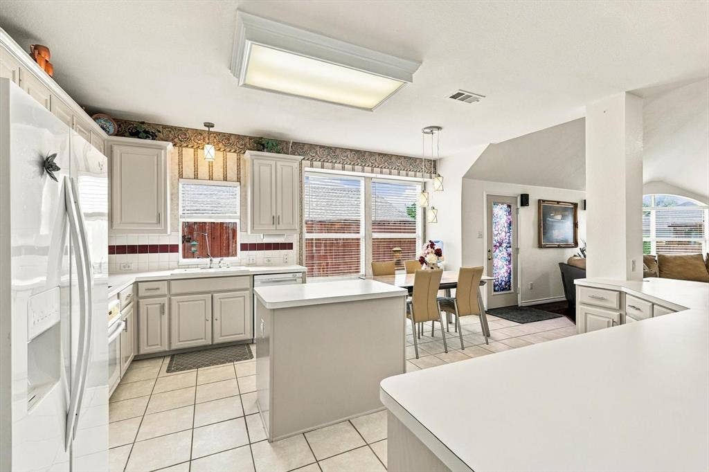 Kitchen with white cabinetry, tile flooring, and a center island