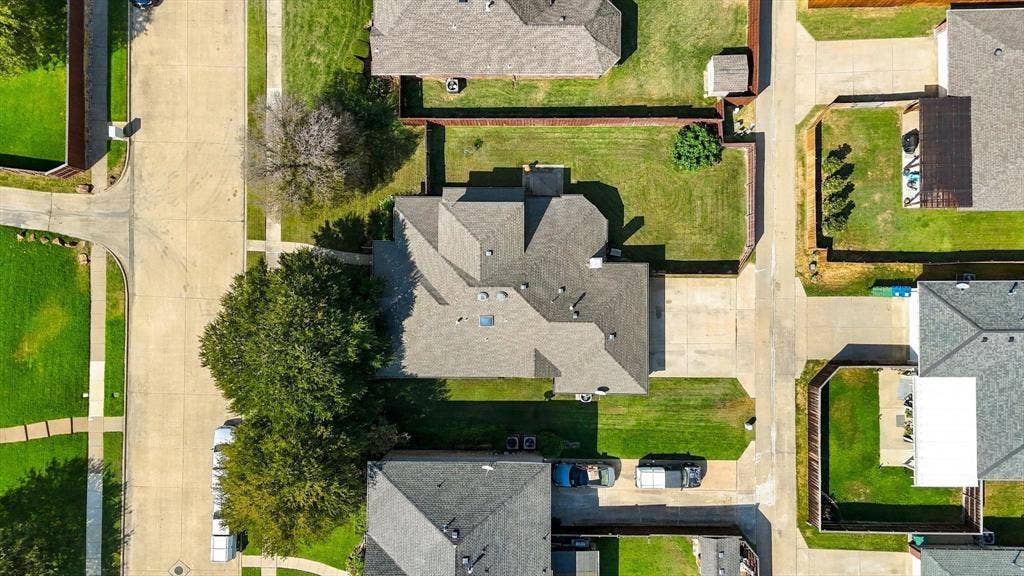 Property features a dark gray shingle roof, green lawn, and mature trees