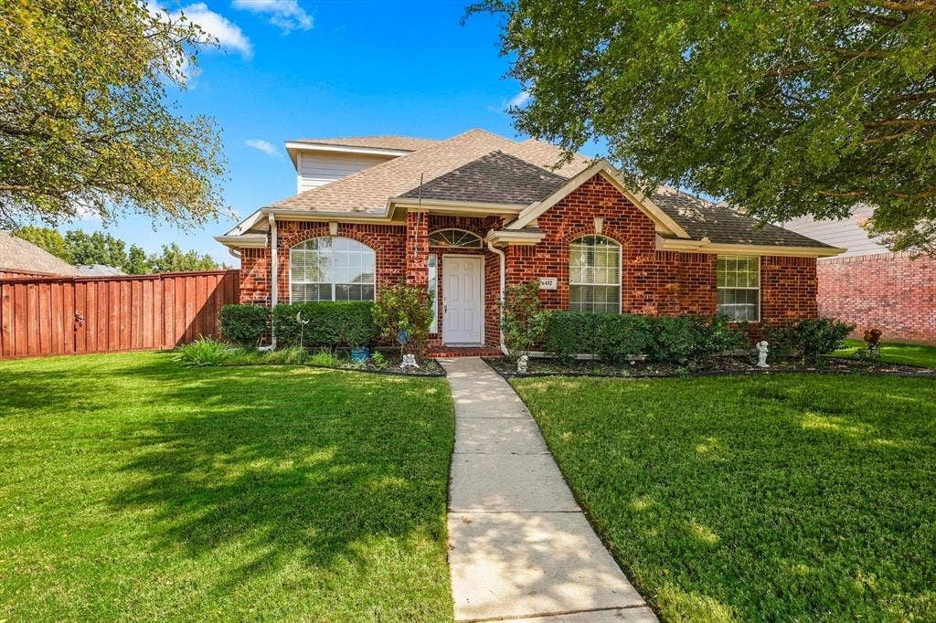 Red brick exterior with white trim, arched windows, covered entryway, and a concrete pathway