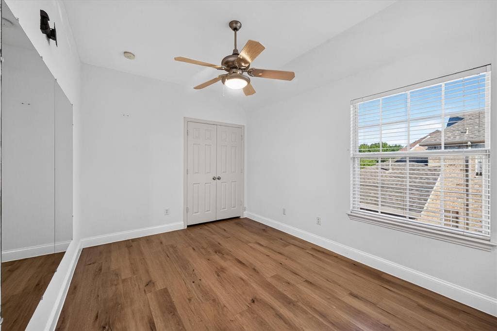 10601 Whispering Pines Drive, Frisco, TX 75033 Wood-finish flooring, ceiling fan with integrated lighting, window with horizontal blinds, built-in bi-fold closet doors, and a full-height wall mirror