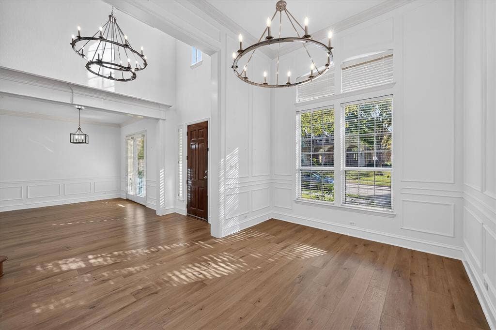 10601 Whispering Pines Drive, Frisco, TX 75033 Hardwood flooring, double-height ceilings, decorative wainscoting, and a prominent chandelier