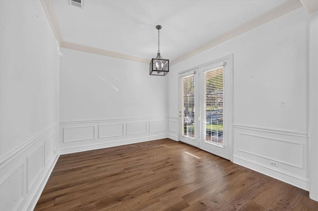 10601 Whispering Pines Drive, Frisco, TX 75033 Wood-finish flooring, crown molding, wainscoting, double glass-paned doors, and a contemporary ceiling fixture