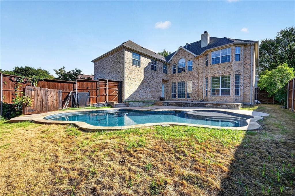10601 Whispering Pines Drive, Frisco, TX 75033 Two-story brick exterior with multiple large windows, a structured in-ground swimming pool, and an integrated spa