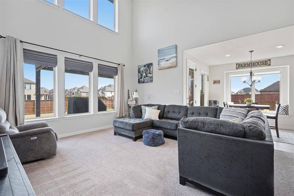 Spacious living area with high ceilings, multiple large windows, and an open concept layout with an adjacent dining space