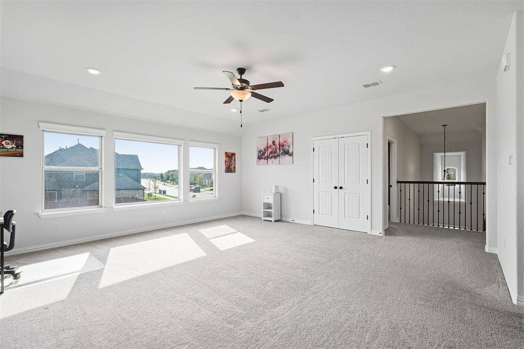 Spacious carpeted room featuring multiple windows, recessed lighting, ceiling fan, and double panel doors
