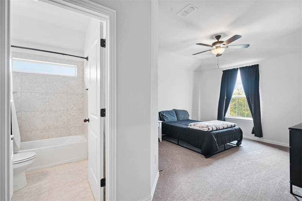 Bedroom with vaulted ceiling, ceiling fan, and carpet flooring