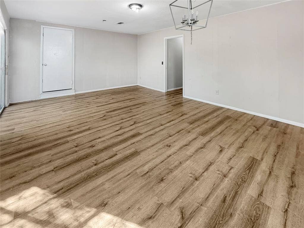 Spacious interior with wood-finish flooring, white walls, and a recessed ceiling light