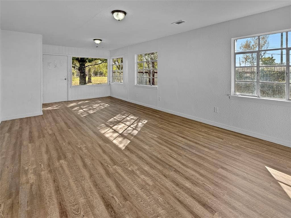Wood-finish flooring throughout, multiple windows, and flush-mount ceiling lights