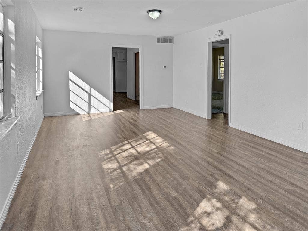 Wood-finish flooring, multiple windows, and a flush mount light fixture