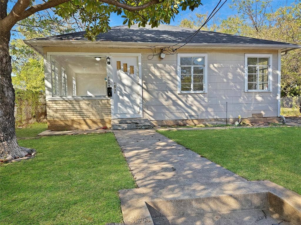 Front exterior featuring a brick foundation, multiple window panes, and a concrete pathway leading to the entrance