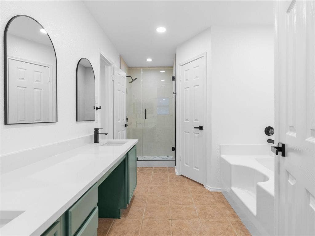 6716 Gold Dust Trail, Dallas, TX 75252 Dual vanity with white countertop and integrated sinks, walk-in shower with clear glass enclosure, matte black fixtures throughout, and a built-in soaking tub