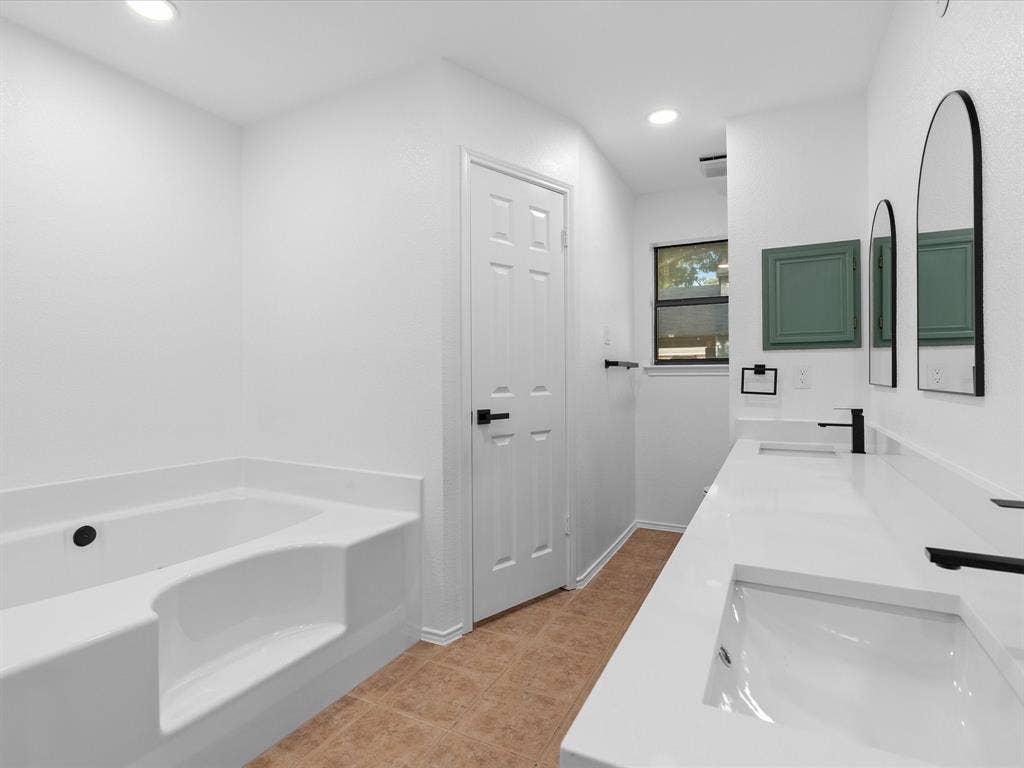 6716 Gold Dust Trail, Dallas, TX 75252 Recessed lighting illuminates a dual-sink vanity with matte black faucets and white countertops