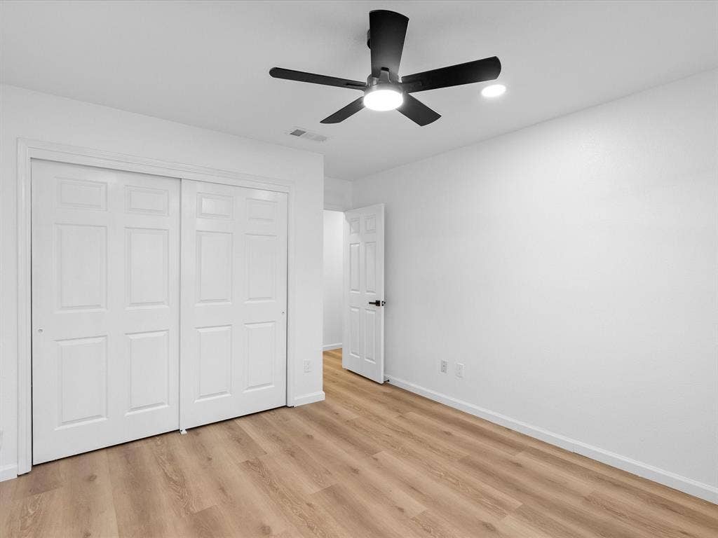 6716 Gold Dust Trail, Dallas, TX 75252 Wood-finish flooring, white walls, white paneled doors, and a black ceiling fan with integrated lighting