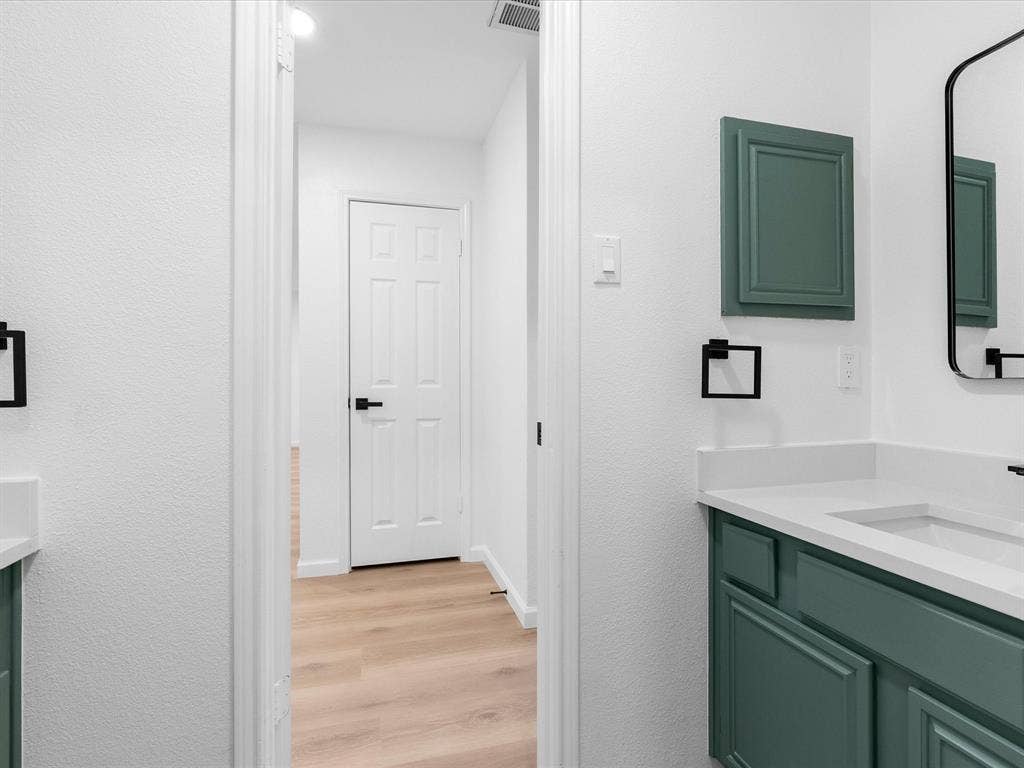 6716 Gold Dust Trail, Dallas, TX 75252 Dual vanity with white countertops and teal cabinetry, featuring integrated sinks and black hardware