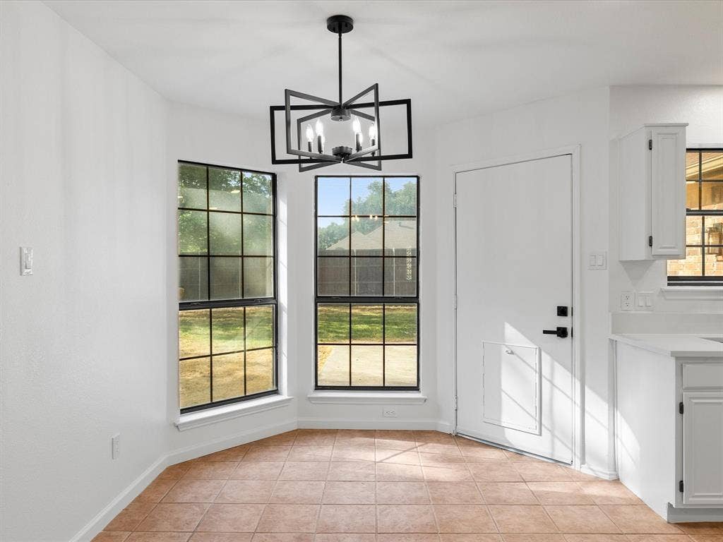 Recessed dining nook with ceramic tile flooring, a modern chandelier, and multiple windows