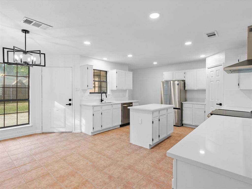 Kitchen featuring white cabinetry, a central island, stainless steel appliances, white countertops, and tile flooring