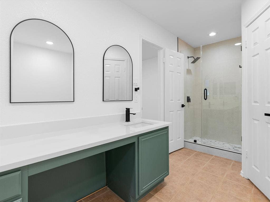 Vanity with emerald-toned cabinetry, white countertop, and integrated sink