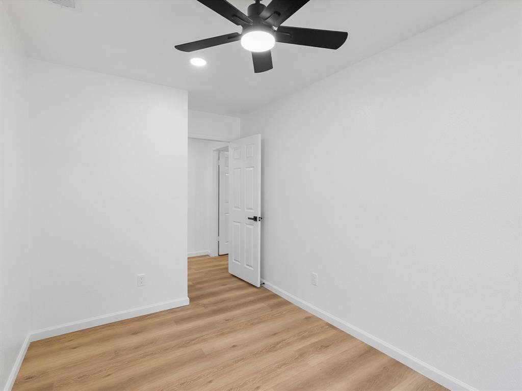Wood-finish flooring, white walls, ceiling fan, and recessed lighting