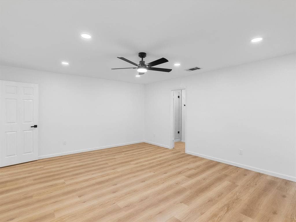 Spacious room with wood-finish flooring, recessed ceiling lighting, a modern ceiling fan, and white paneled doors