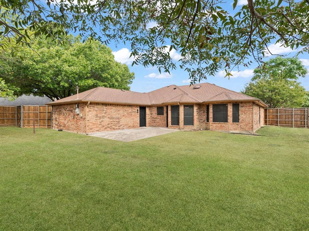 Expansive backyard featuring a manicured lawn, a large concrete patio, and a privacy fence