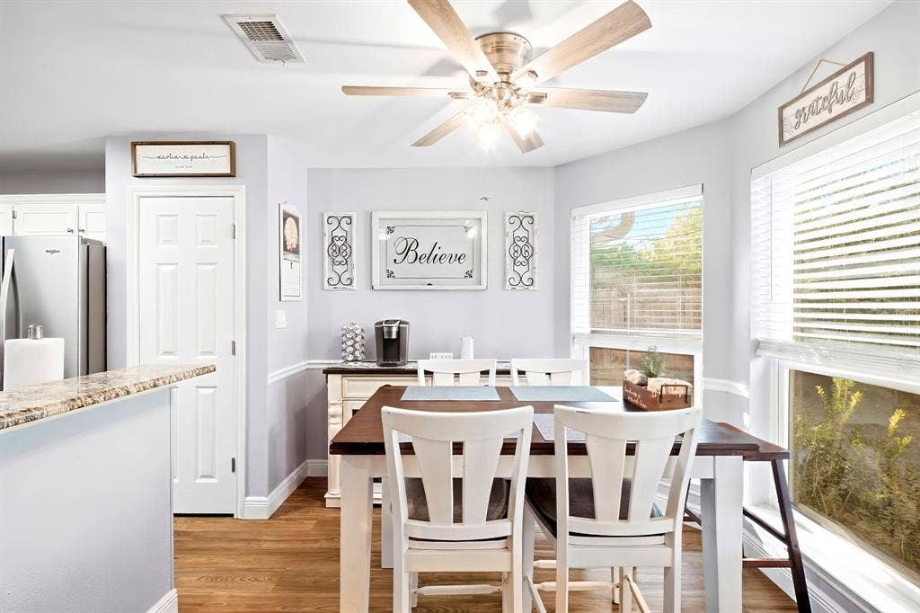 506 Amy Jo Circle, Aubrey, TX 76227 Open-concept dining area featuring wood-finish flooring, a ceiling fan with integrated lighting, and multiple windows with blinds