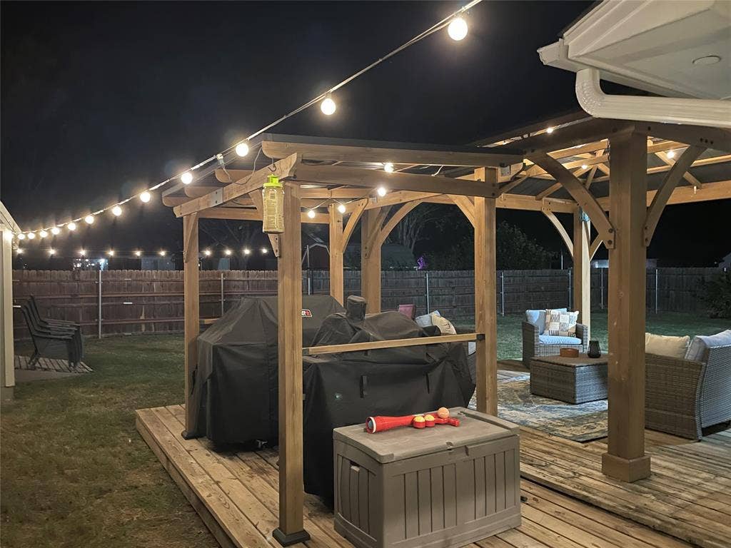 506 Amy Jo Circle, Aubrey, TX 76227 Expansive backyard deck featuring a wooden pergola, string lighting, and a privacy fence