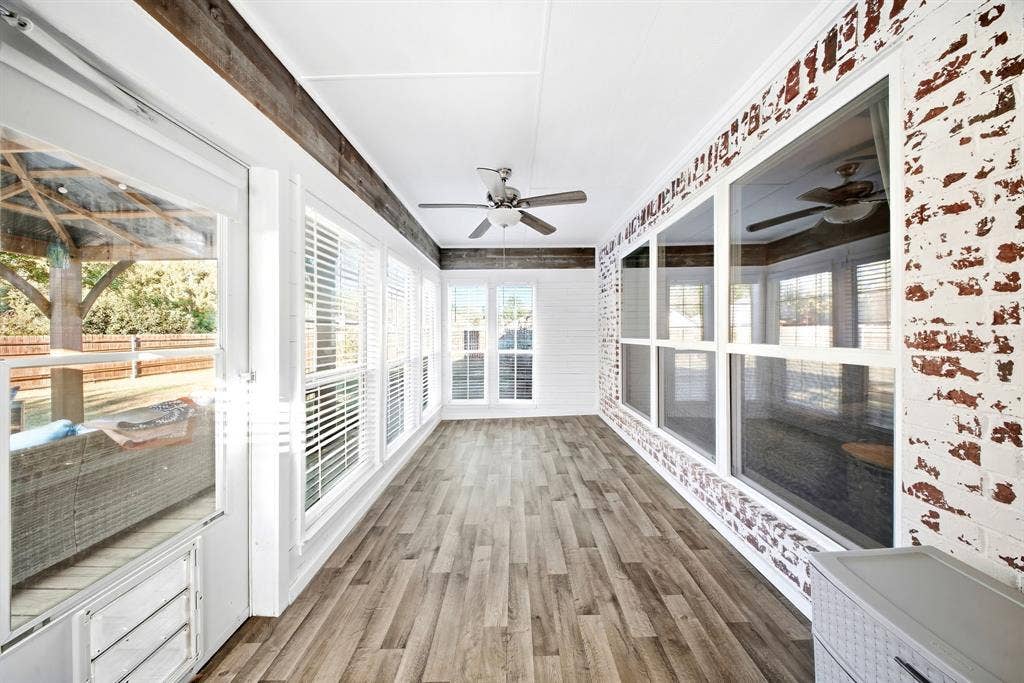 506 Amy Jo Circle, Aubrey, TX 76227 Enclosed sunroom featuring multiple large windows, wood-finish flooring, a ceiling fan, and exposed brick accents