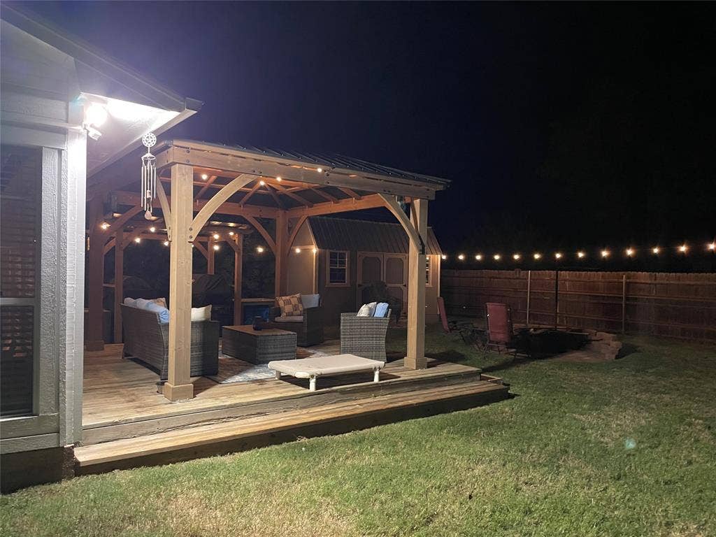 506 Amy Jo Circle, Aubrey, TX 76227 Wood-finish deck with a built-in pergola featuring string lighting, a manicured lawn, and a privacy fence