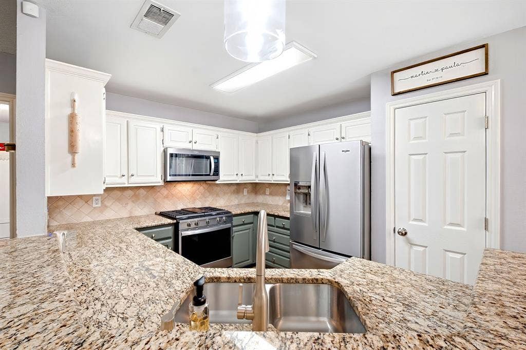 506 Amy Jo Circle, Aubrey, TX 76227 Granite countertops, stainless steel appliances, white upper cabinetry, and a tile backsplash