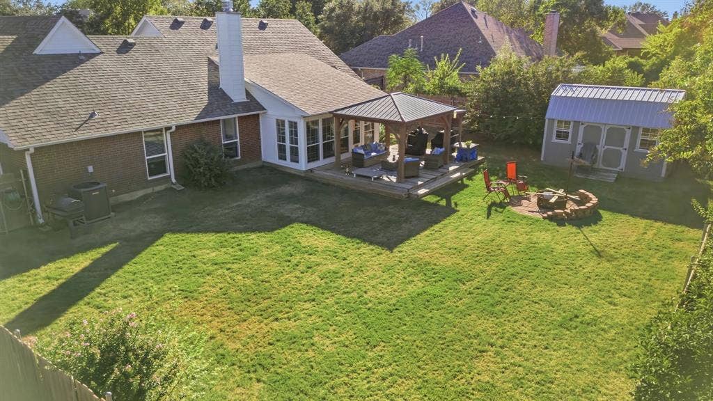 506 Amy Jo Circle, Aubrey, TX 76227 Expansive backyard featuring a large lawn, a wooden deck with a gazebo, a stone fire pit area, and a storage shed