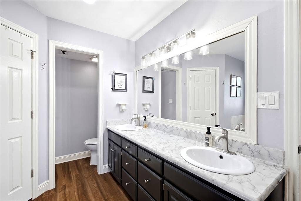 506 Amy Jo Circle, Aubrey, TX 76227 Dual sink vanity with dark wood-finish cabinetry, white framed mirror, and wood-finish flooring