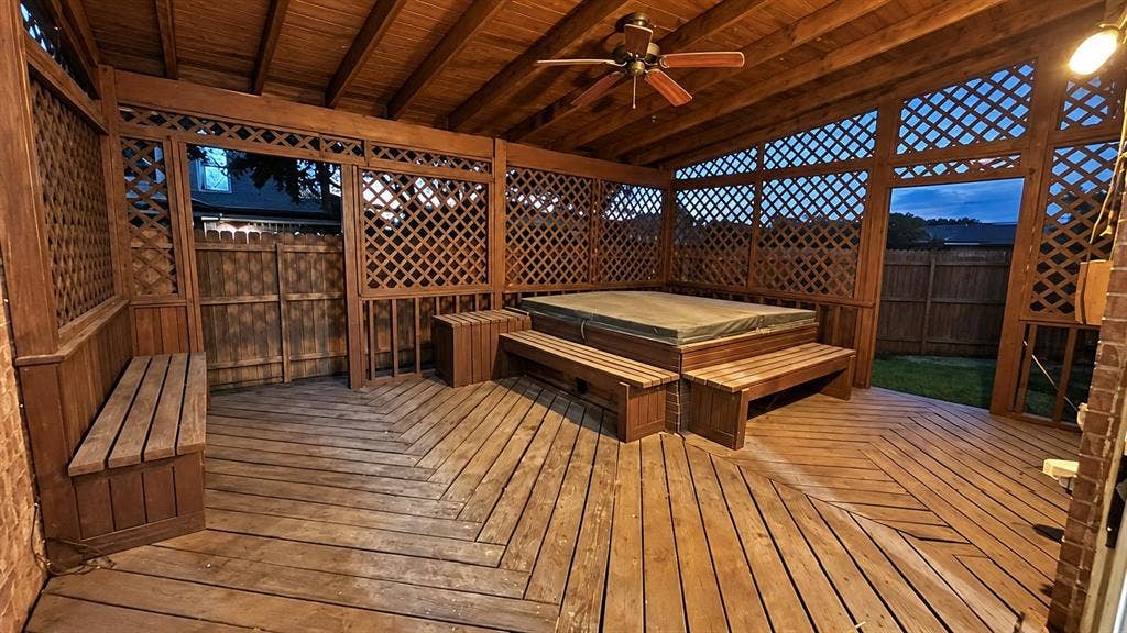 Wooden deck with geometric pattern, lattice privacy screens, built-in benches, and a ceiling fan
