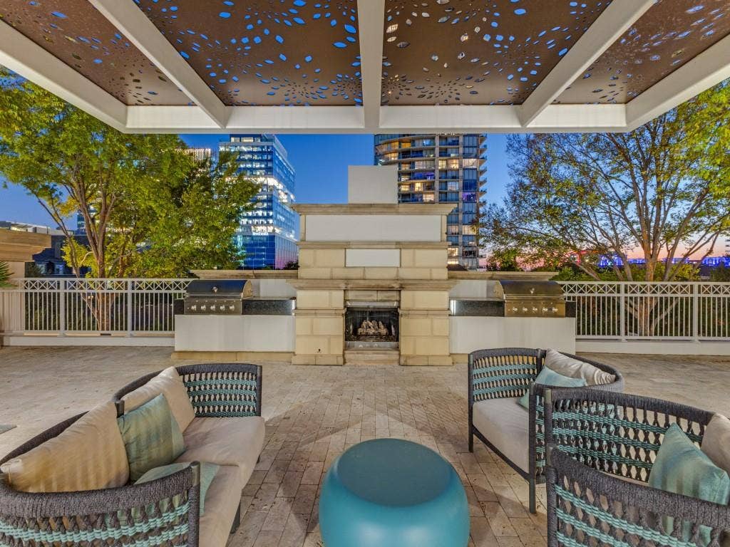 2300 Wolf Street, #14A, Dallas, TX 75201 Expansive outdoor terrace featuring a built-in fireplace, two integrated grills, and a decorative perforated ceiling