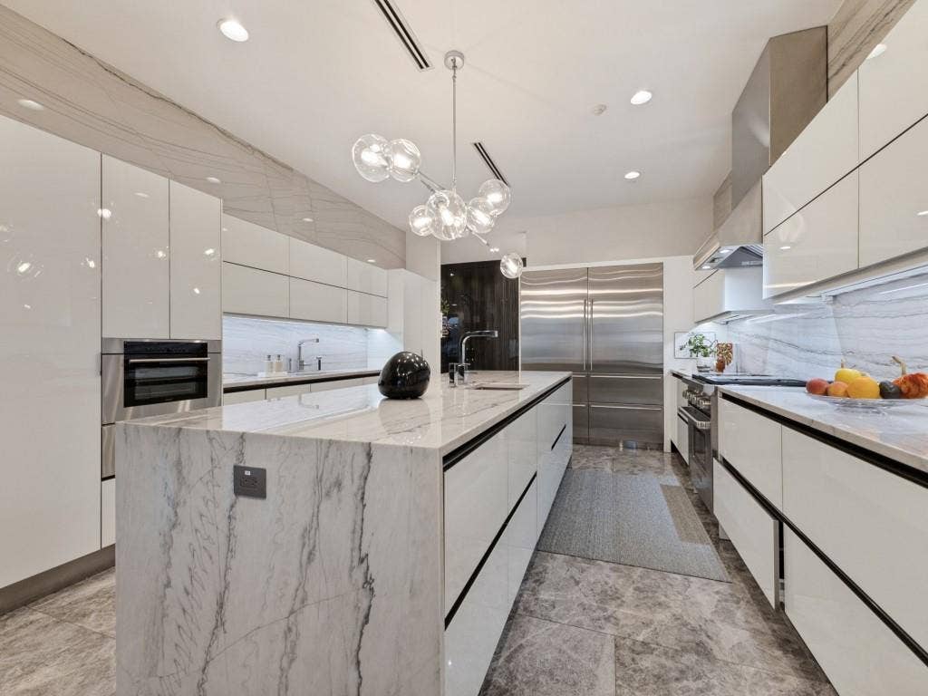 2300 Wolf Street, #14A, Dallas, TX 75201 Integrated stainless steel appliances, marble-clad waterfall island, polished white cabinetry, contemporary chandelier, and recessed lighting
