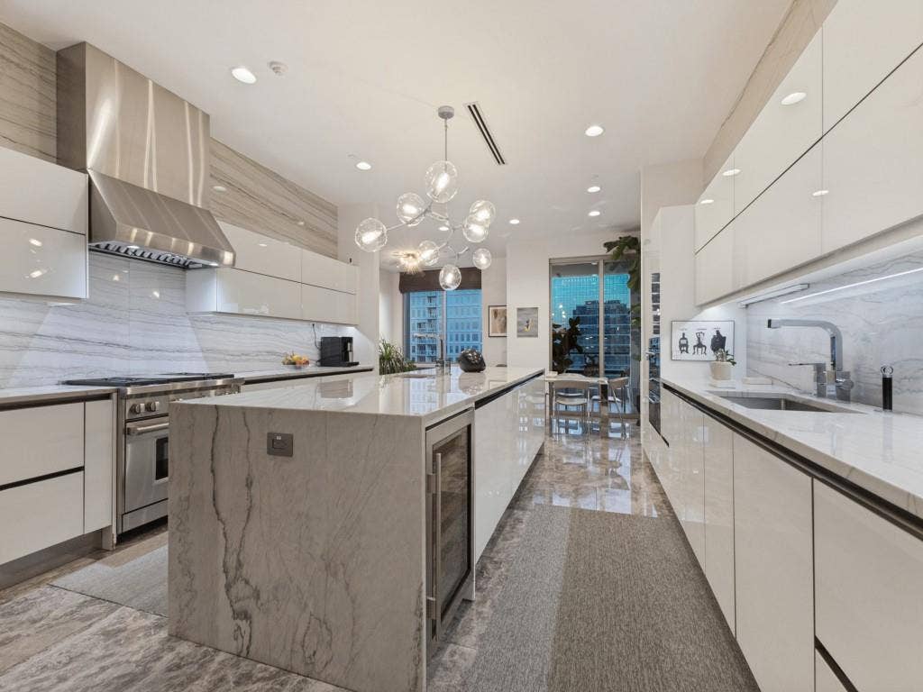 2300 Wolf Street, #14A, Dallas, TX 75201 Gourmet kitchen featuring a waterfall island, integrated wine refrigerator, stainless steel appliances, and sleek flat-panel cabinetry