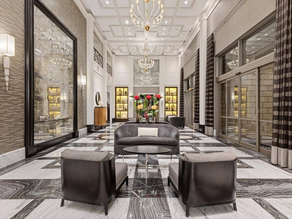 2300 Wolf Street, #14A, Dallas, TX 75201 Coffered ceiling with multiple chandeliers, full-height wall mirror, illuminated display shelving, floor-to-ceiling glass paneling, and patterned tile flooring