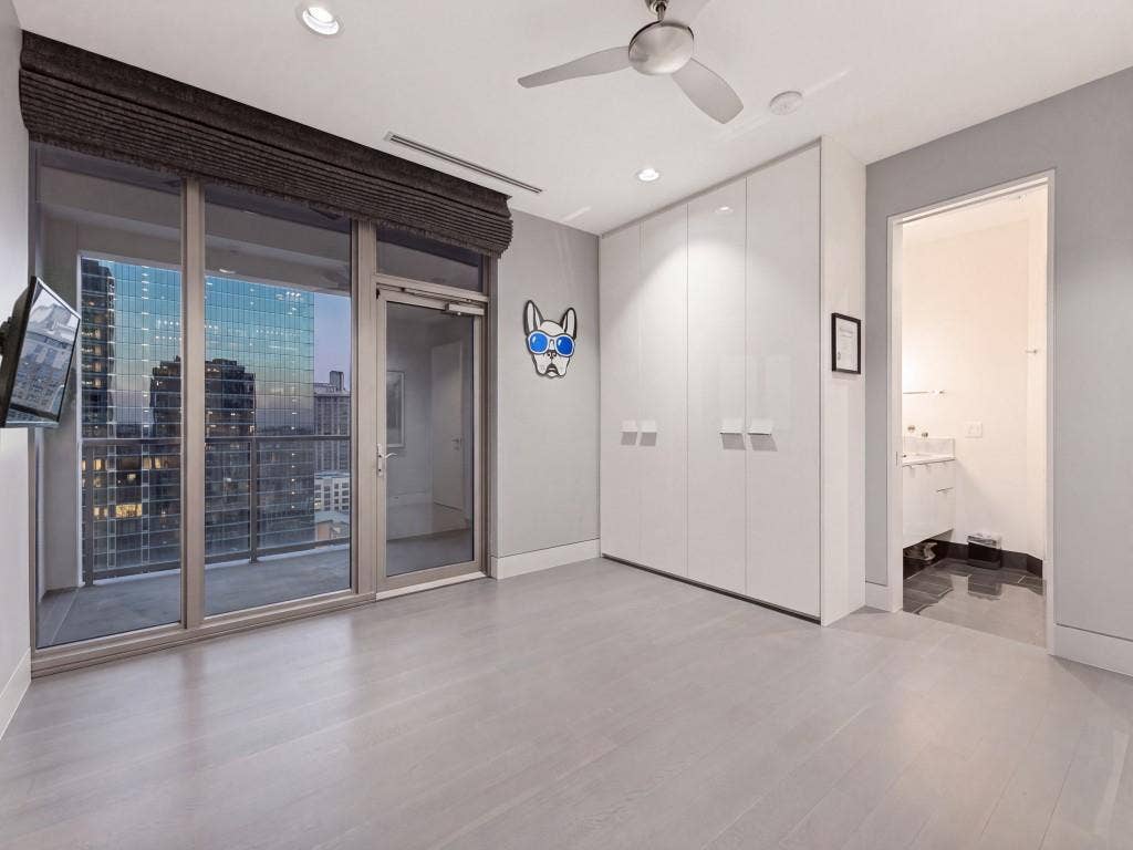 2300 Wolf Street, #14A, Dallas, TX 75201 Floor-to-ceiling glass wall with metal-frame balcony door, built-in floor-to-ceiling high-gloss cabinetry, recessed ceiling lighting, ceiling fan, and wood-finish flooring