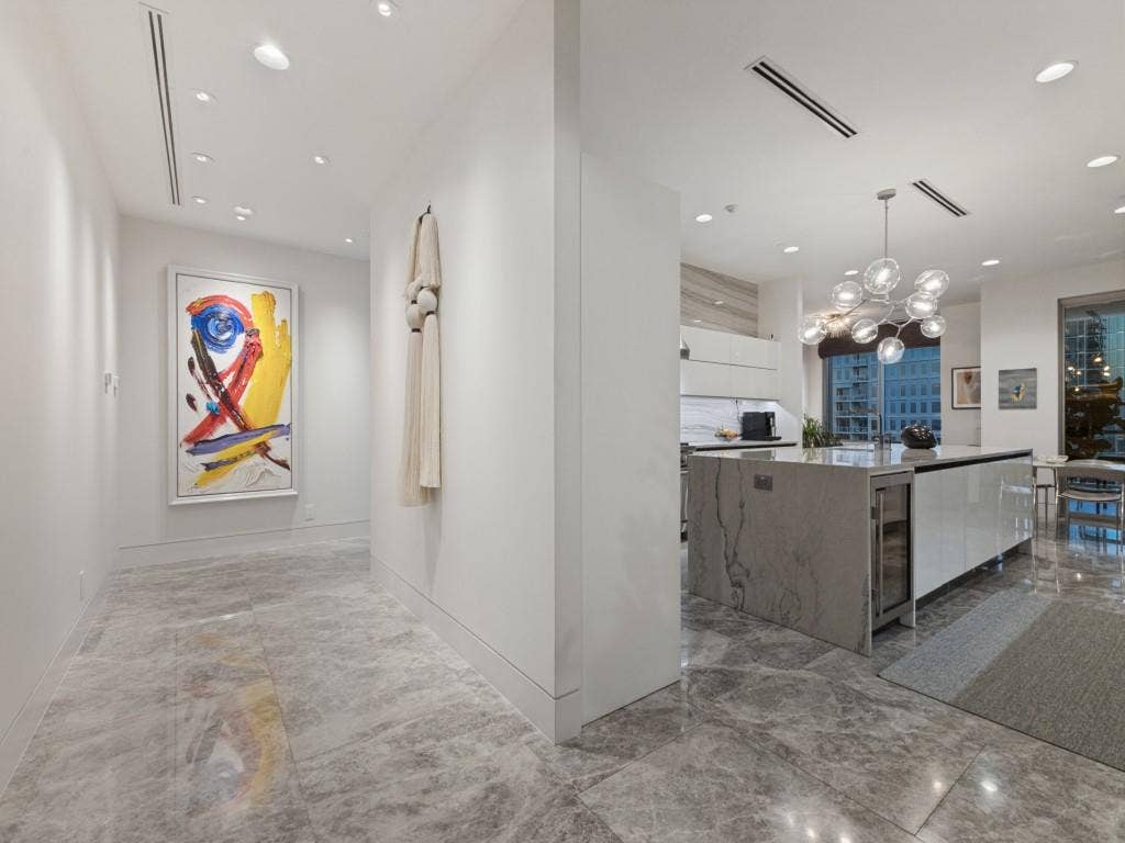2300 Wolf Street, #14A, Dallas, TX 75201 Recessed lighting throughout, gray veined tile flooring, large kitchen island with integrated beverage cooler, contemporary chandelier, and high ceilings
