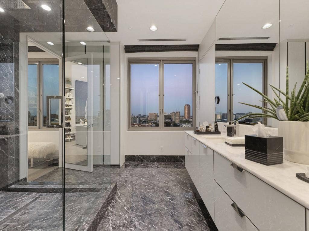 2300 Wolf Street, #14A, Dallas, TX 75201 Shower enclosure with glass paneling, grey marble-finish flooring, dual-sink vanity with white countertop, and expansive windows