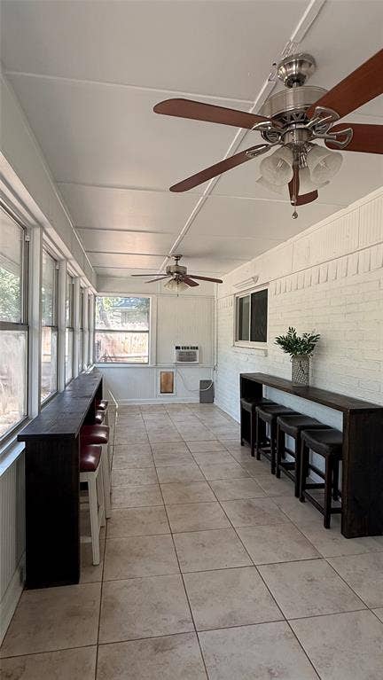 8513 Ravenswood Road, Granbury, TX 76049 Enclosed sunroom featuring tile flooring, multiple ceiling fans with integrated lighting, and extensive wall of windows overlooking the peaceful backyard. Also has a doggy door that leads to it's own secured area.