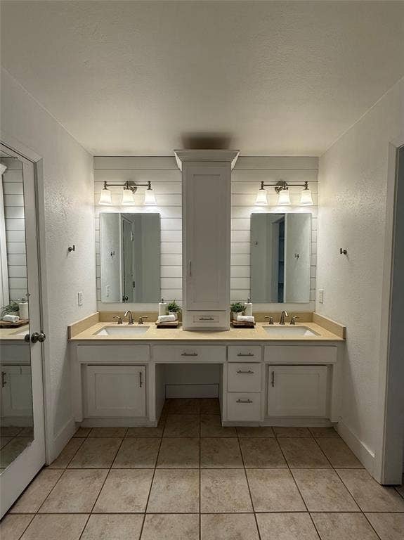 8513 Ravenswood Road, Granbury, TX 76049 Dual vanity with sinks, light-toned countertops, white shaker-style cabinetry, continued shiplap and a central built-in storage tower. The closet is to the left and separate shower and toilet are the the right.
