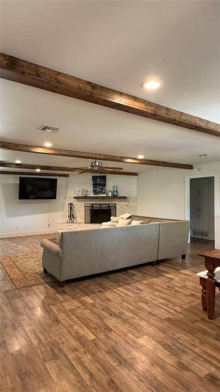 8513 Ravenswood Road, Granbury, TX 76049 Wood-finish flooring throughout, ceiling with exposed wood beams and recessed lighting, fireplace with stone surround and shiplap accent wall, and a ceiling fan