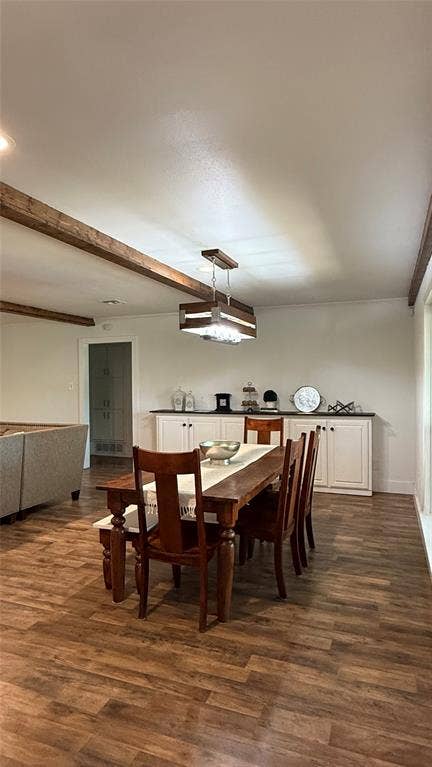 8513 Ravenswood Road, Granbury, TX 76049 Wood-finish flooring, exposed ceiling beams, built-in lower cabinetry, dark countertop, and a contemporary chandelier