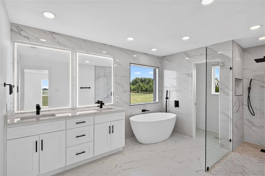 15166 FM 3133, Anna, TX 75409 Bright bathroom featuring a dual vanity with white cabinetry and light-toned countertops, two illuminated mirrors, a freestanding soaking tub, and a spacious glass-enclosed shower with contrasting dark fixtures