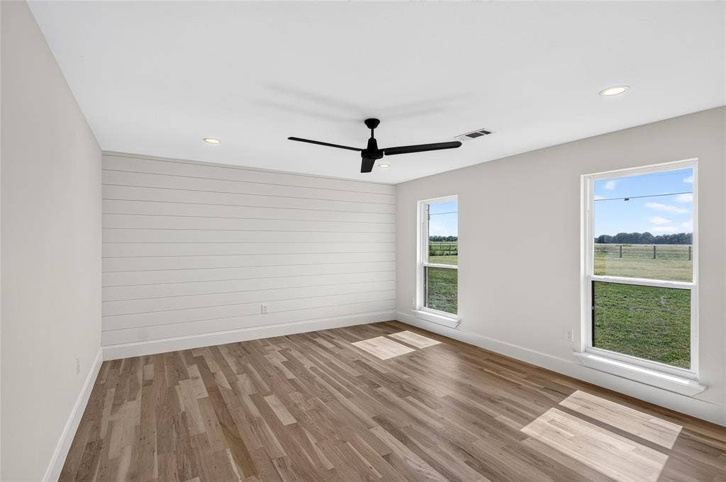 15166 FM 3133, Anna, TX 75409 Spacious room featuring wood-finish flooring, a shiplap accent wall, a ceiling fan, recessed lighting, and two windows