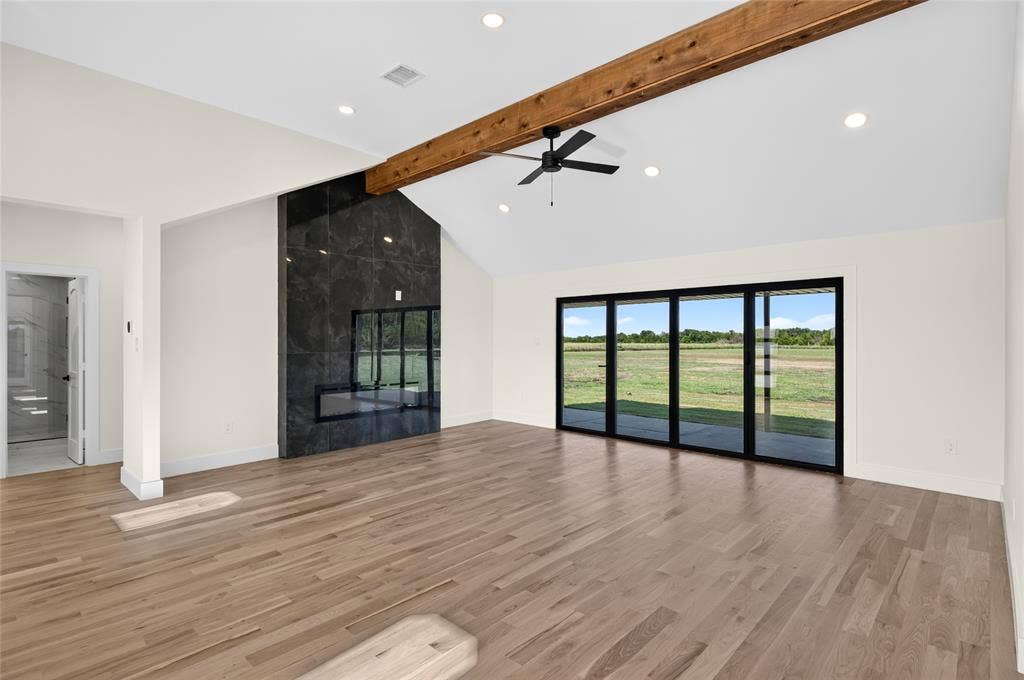15166 FM 3133, Anna, TX 75409 Spacious living area featuring high vaulted ceilings, light wood-finish flooring, and a striking dark stone fireplace