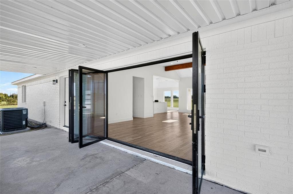 15166 FM 3133, Anna, TX 75409 Covered concrete patio with bi-fold glass doors opening to an interior space featuring wood-finish flooring and white walls