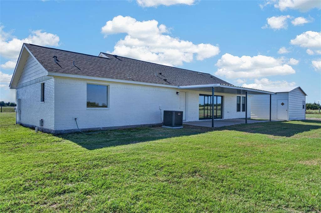 15166 FM 3133, Anna, TX 75409 White brick exterior with an attached covered patio featuring a concrete slab and a detached storage shed