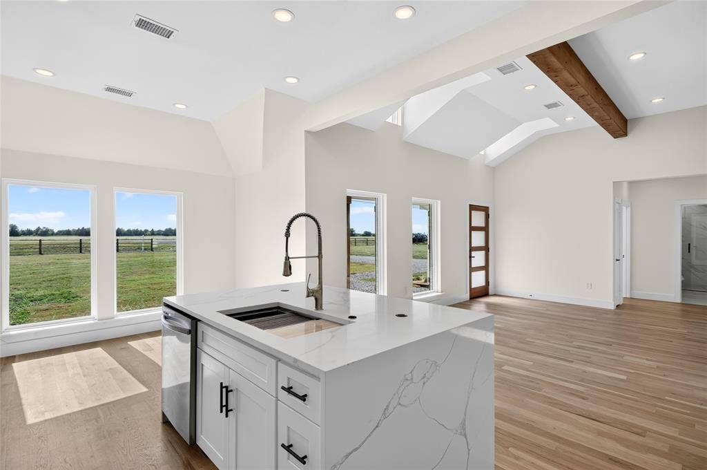 15166 FM 3133, Anna, TX 75409 Spacious open-concept interior featuring light wood-finish flooring and vaulted ceilings with exposed wood beams