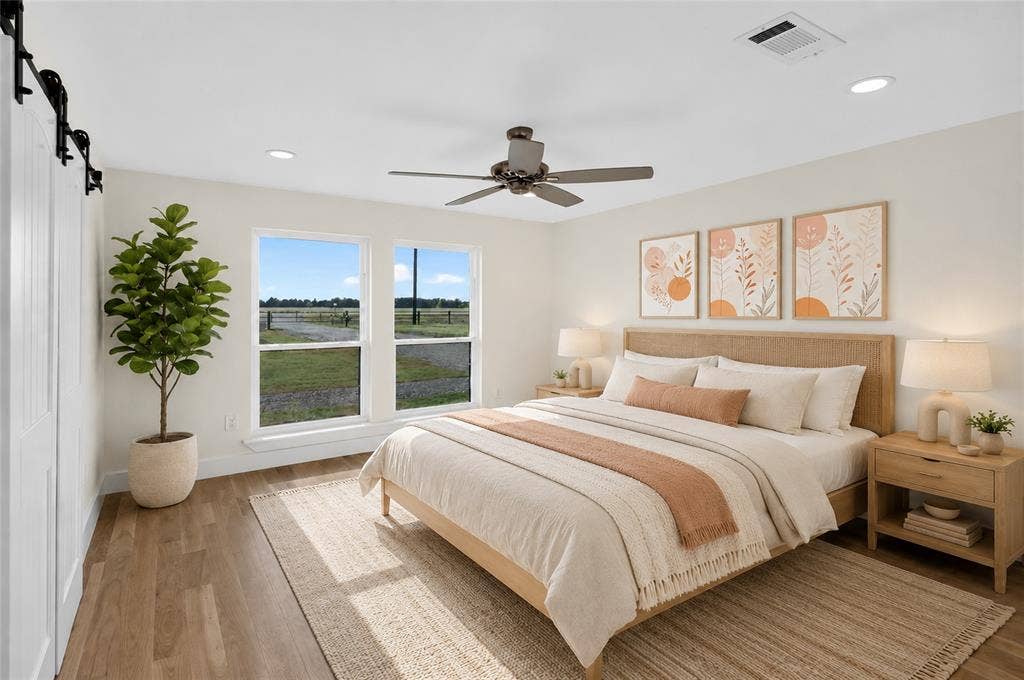 15166 FM 3133, Anna, TX 75409 Dual windows overlooking a field, wood-finish flooring, a ceiling fan with integrated lighting, recessed lighting, and a white barn door - Virtually Staged